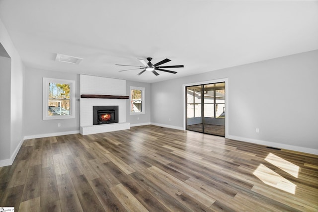 unfurnished living room with a wealth of natural light, wood finished floors, visible vents, and baseboards