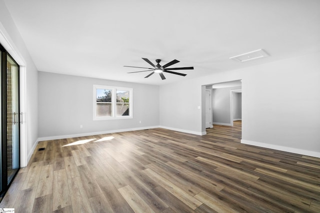 empty room with a ceiling fan, wood finished floors, attic access, and baseboards