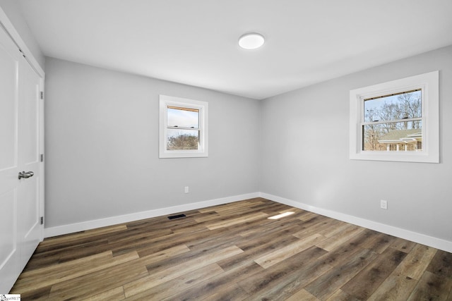 unfurnished room featuring baseboards, wood finished floors, and a healthy amount of sunlight