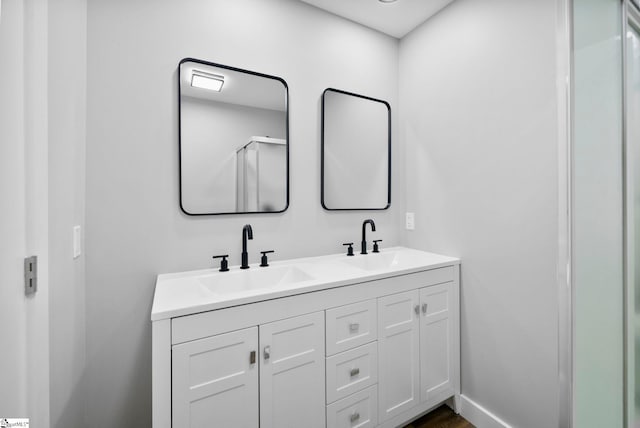 full bathroom featuring a sink, baseboards, and double vanity