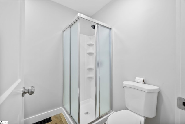 full bathroom featuring toilet, a shower stall, visible vents, and wood finished floors