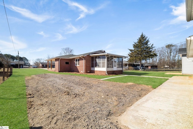 view of front of house with a sunroom, fence, brick siding, and a front yard