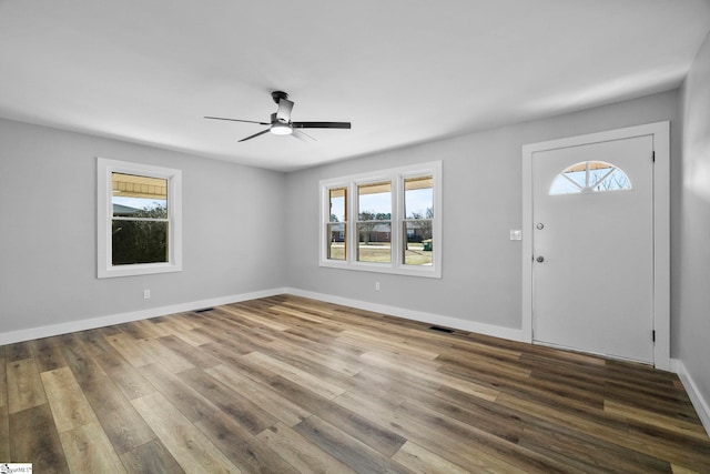 foyer with ceiling fan, visible vents, baseboards, and wood finished floors