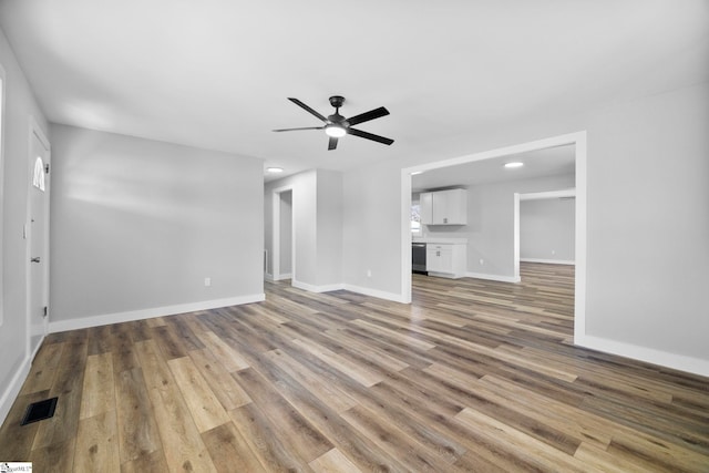 unfurnished living room featuring baseboards, visible vents, ceiling fan, and wood finished floors