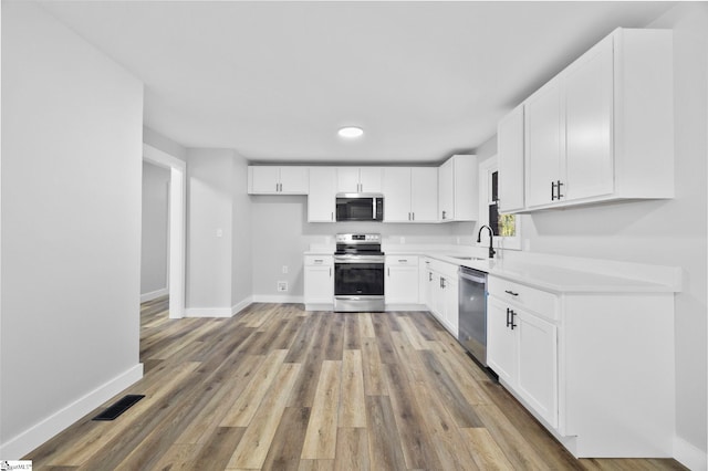 kitchen with visible vents, appliances with stainless steel finishes, light wood-style floors, a sink, and baseboards