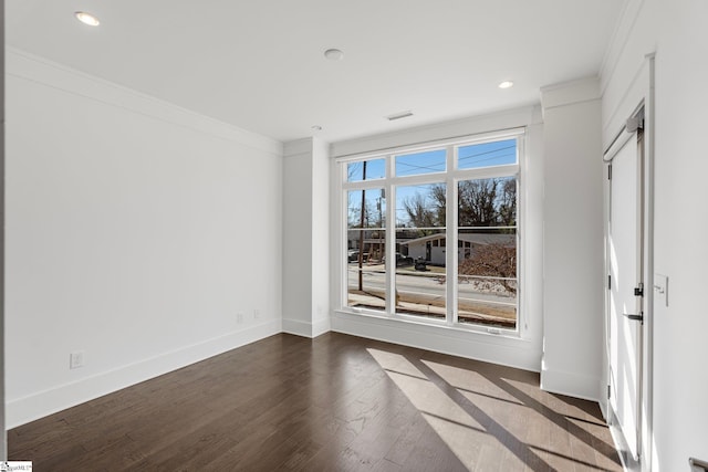 unfurnished room with dark wood-style flooring, recessed lighting, visible vents, ornamental molding, and baseboards