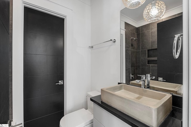 full bath featuring a tile shower, vanity, and toilet