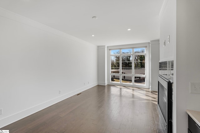 unfurnished living room with visible vents, baseboards, dark wood-type flooring, crown molding, and recessed lighting