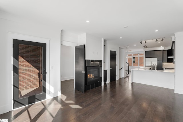 living room with recessed lighting, baseboards, dark wood finished floors, and a glass covered fireplace