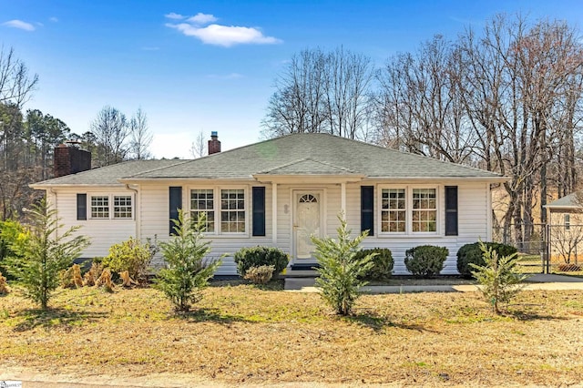 view of front of home with roof with shingles, fence, and a chimney