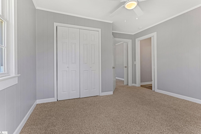 unfurnished bedroom featuring ornamental molding, a closet, carpet, and a ceiling fan