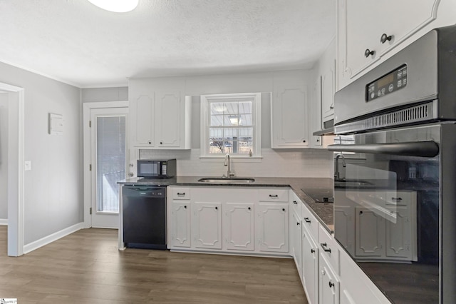 kitchen with dark countertops, white cabinets, a sink, wood finished floors, and black appliances