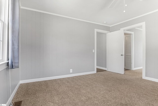 carpeted empty room featuring baseboards, visible vents, and crown molding