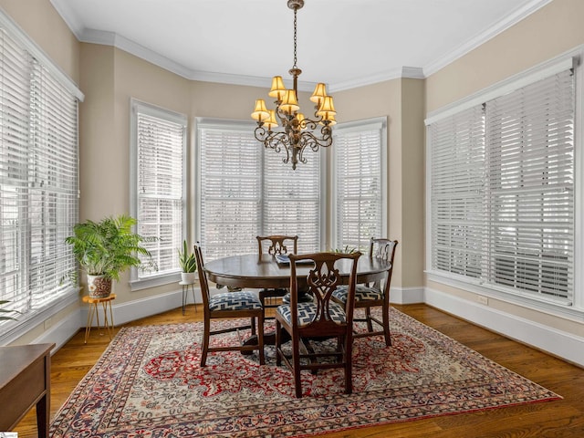 dining space featuring a notable chandelier, baseboards, wood finished floors, and crown molding