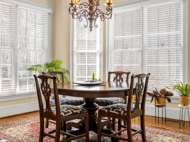 dining area featuring baseboards, a notable chandelier, and wood finished floors