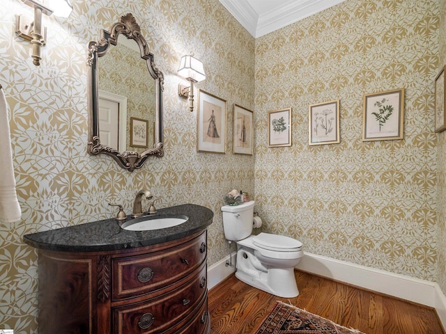 bathroom featuring wallpapered walls, toilet, wood finished floors, crown molding, and vanity