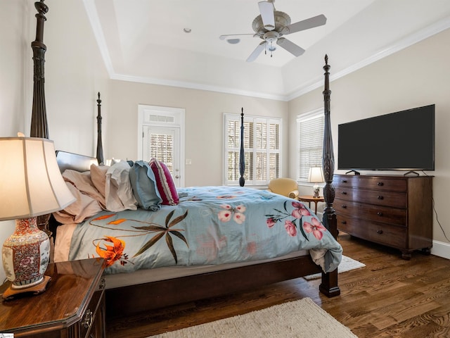 bedroom with a raised ceiling, ornamental molding, a ceiling fan, wood finished floors, and baseboards