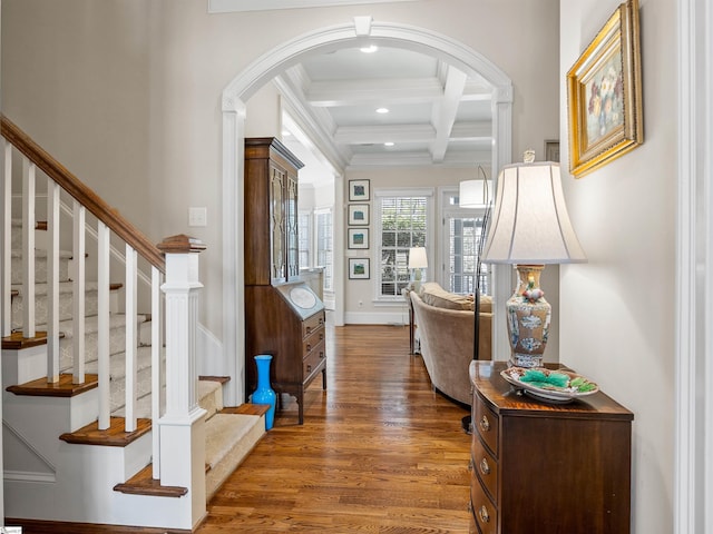 entrance foyer featuring arched walkways, recessed lighting, coffered ceiling, wood finished floors, and beamed ceiling