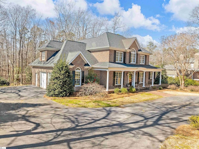 view of front facade with covered porch, driveway, and brick siding