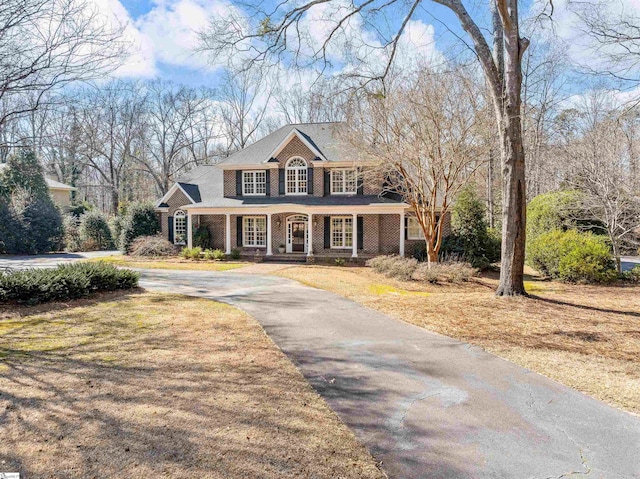 view of front of home featuring a porch, aphalt driveway, and brick siding