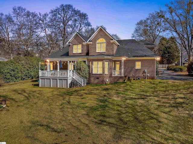 view of front of property featuring brick siding, stairway, a porch, and a front yard