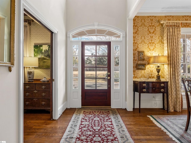 entrance foyer with wallpapered walls, crown molding, baseboards, and wood finished floors