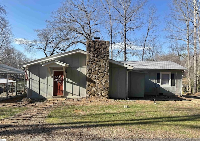 view of side of property with board and batten siding, metal roof, a chimney, and a lawn