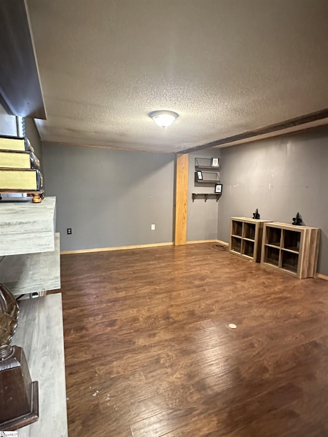 finished below grade area with a textured ceiling, wood finished floors, and baseboards