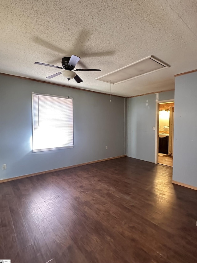 empty room featuring baseboards, wood finished floors, attic access, and a ceiling fan