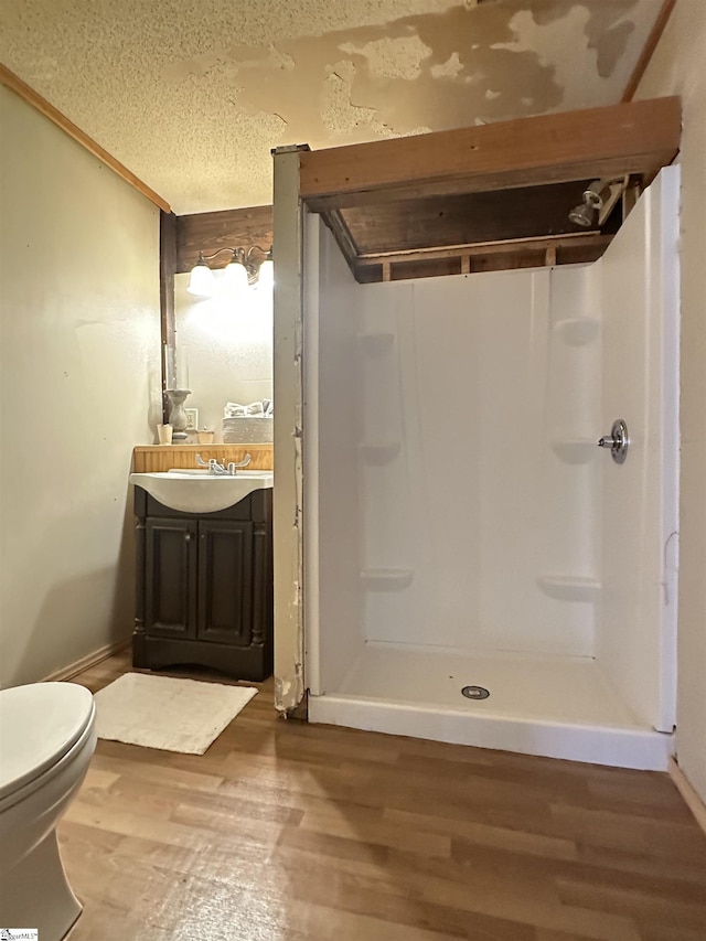 full bath featuring a stall shower, a textured ceiling, wood finished floors, and vanity