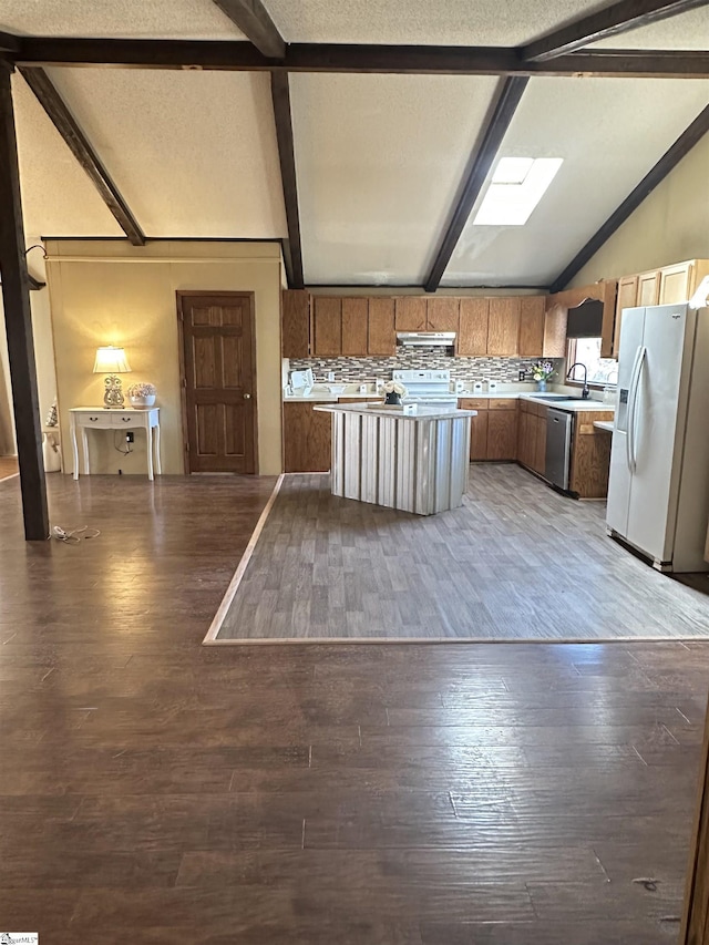 kitchen with white appliances, vaulted ceiling with skylight, light countertops, and wood finished floors