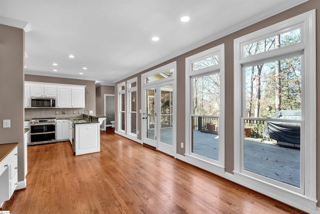 kitchen with crown molding, light wood finished floors, tasteful backsplash, appliances with stainless steel finishes, and a sink