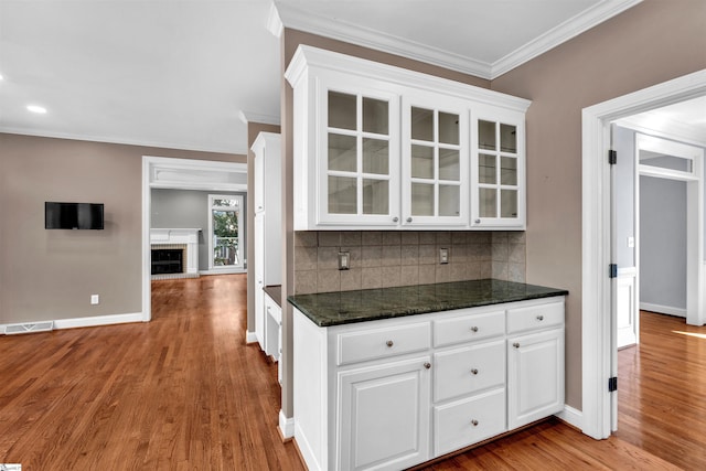 kitchen featuring glass insert cabinets, white cabinets, visible vents, and tasteful backsplash