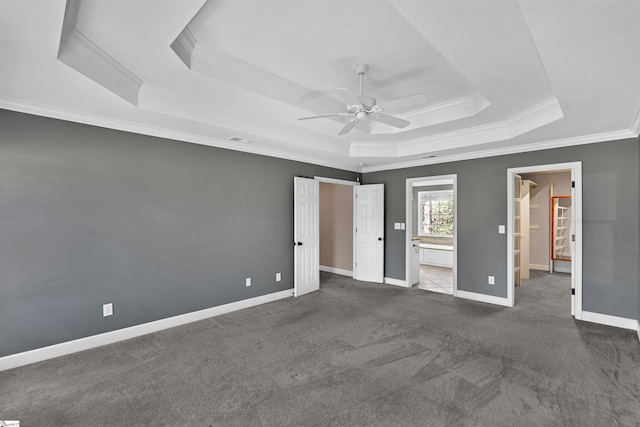 unfurnished bedroom featuring ornamental molding, dark colored carpet, a raised ceiling, and baseboards