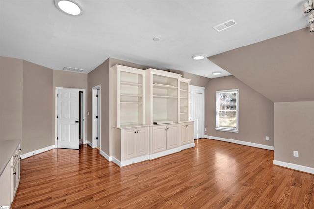 bonus room featuring lofted ceiling, light wood-style flooring, visible vents, and baseboards