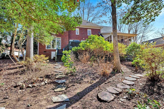 rear view of house with a sunroom, brick siding, crawl space, and stairs