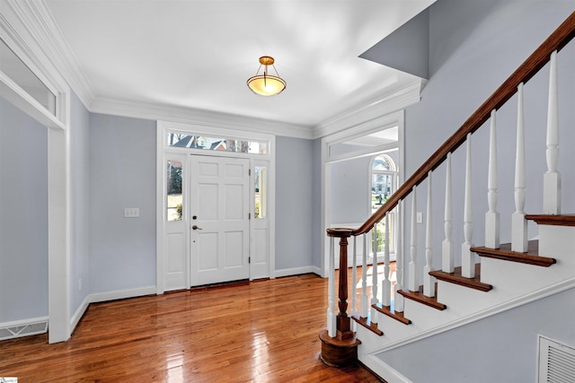 foyer entrance with ornamental molding, hardwood / wood-style flooring, visible vents, and baseboards