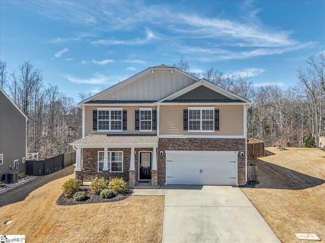 craftsman-style home with concrete driveway, an attached garage, central AC unit, board and batten siding, and a front lawn