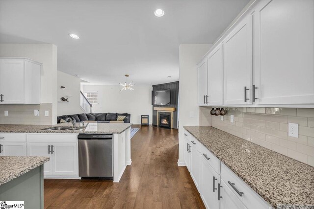 kitchen with dark wood finished floors, white cabinets, dishwasher, open floor plan, and a sink