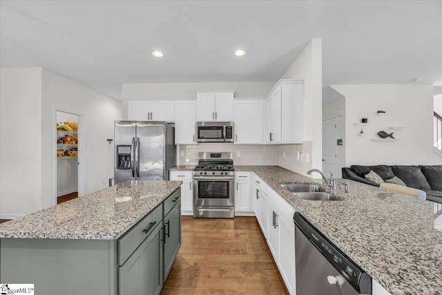 kitchen featuring dark wood-style flooring, a sink, open floor plan, appliances with stainless steel finishes, and backsplash