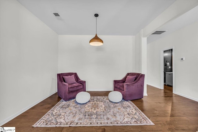 living area with baseboards, visible vents, and wood finished floors