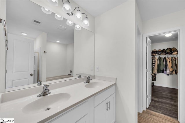 bathroom with double vanity, wood finished floors, a sink, and visible vents