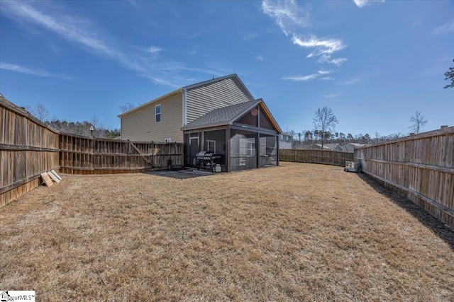 rear view of house with a sunroom, a fenced backyard, and a yard