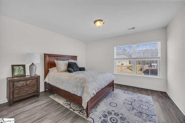 bedroom featuring visible vents, baseboards, and wood finished floors