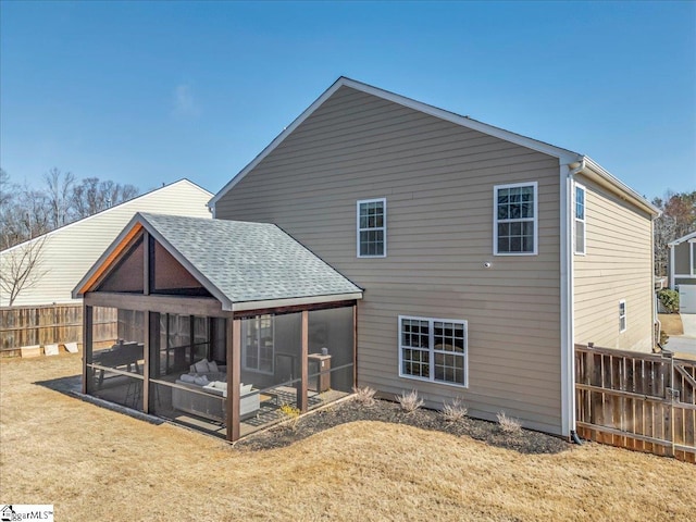 rear view of house with a yard, a sunroom, and fence