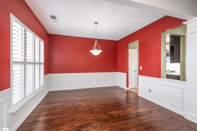 unfurnished dining area with hardwood / wood-style flooring, visible vents, and a wainscoted wall