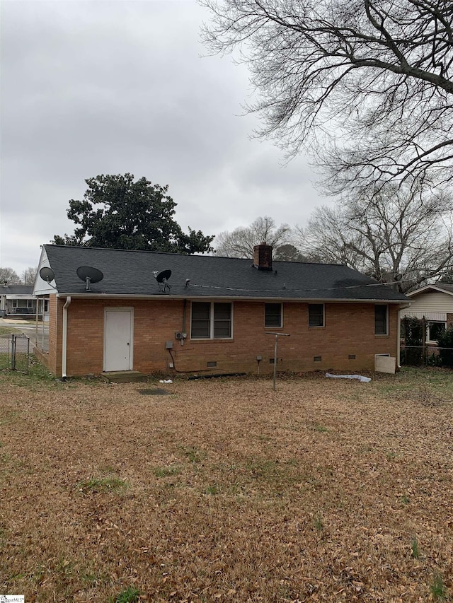 back of property featuring crawl space, brick siding, fence, and a chimney