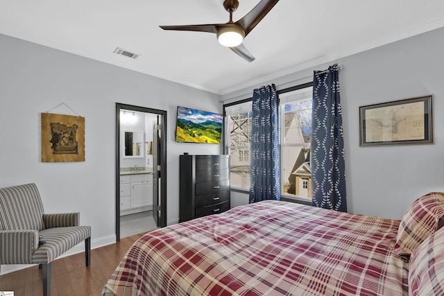 bedroom featuring a sink, wood finished floors, visible vents, baseboards, and ornamental molding