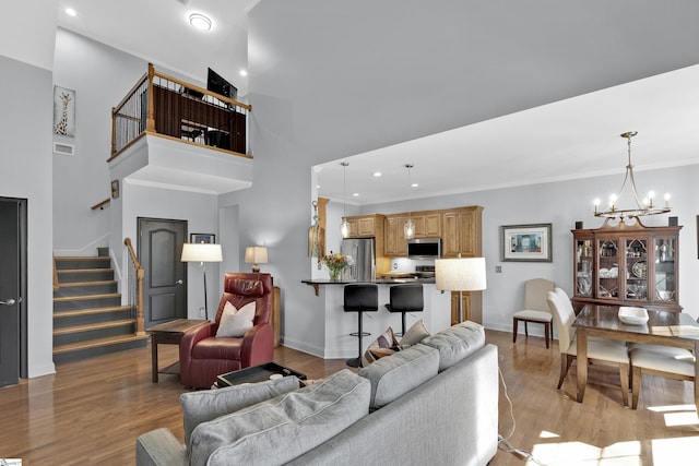 living room with stairs, baseboards, light wood-style flooring, and a notable chandelier