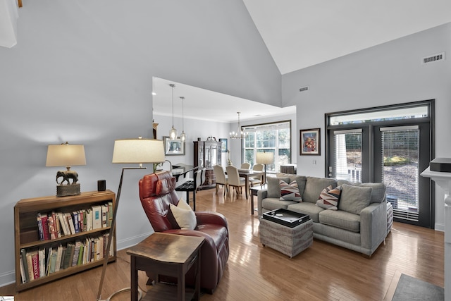 living room with a chandelier, visible vents, high vaulted ceiling, and wood finished floors